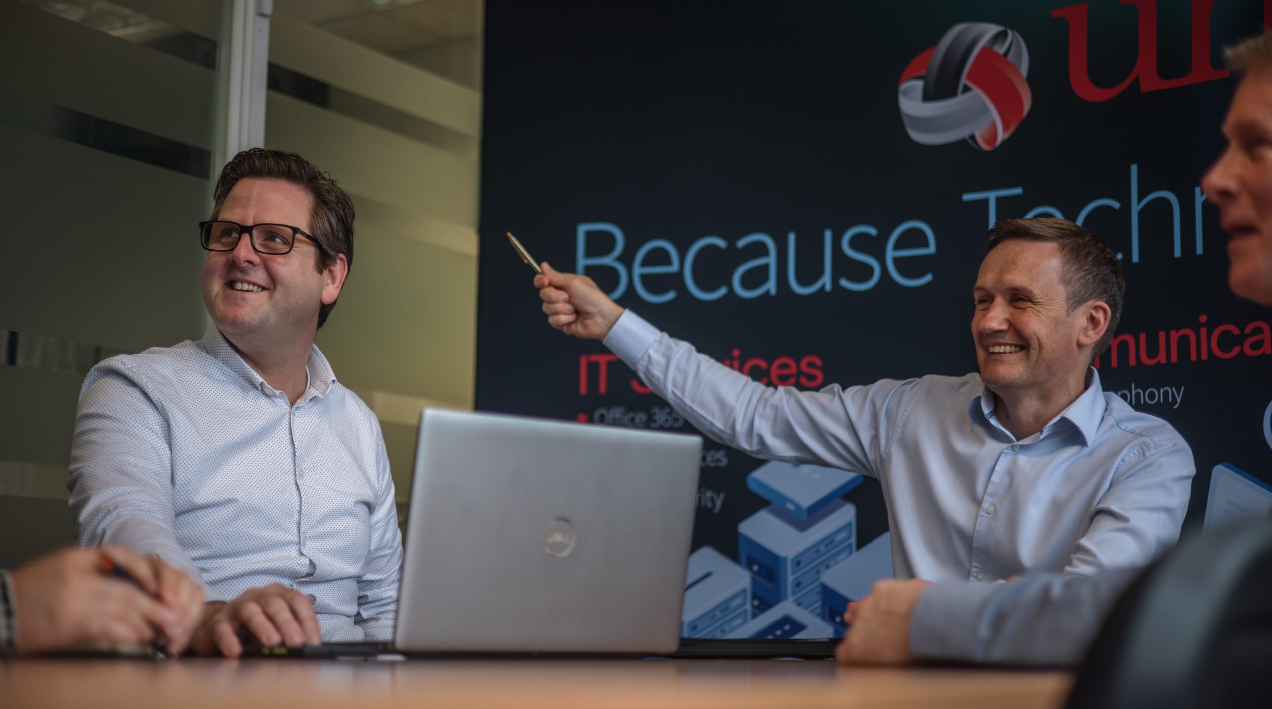 Two of the directors at The Unite Group in a meeting with a laptop and banner backdrop