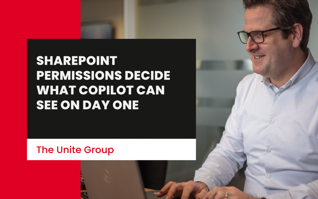 A Unite group employee sat at a desk on a computer similing